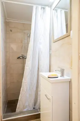 a bathroom with a shower with a sink and a mirror at KARIOKA apartman in Belgrade