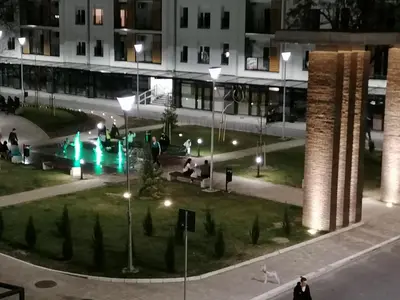 a group of people sitting in a park at night at Zemunske Kapije Yellow Gate in Novi Grad