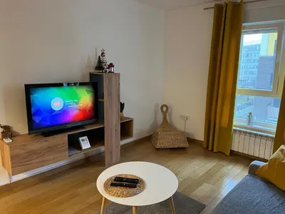 a living room with a flat screen tv and a table at Zemunske Kapije Yellow Gate in Novi Grad