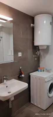 a bathroom with a sink and a washing machine at Zemunske Kapije Yellow Gate in Novi Grad