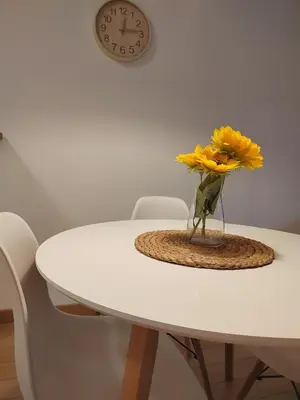 a vase of yellow flowers on a table with a clock at Zemunske Kapije Yellow Gate in Novi Grad