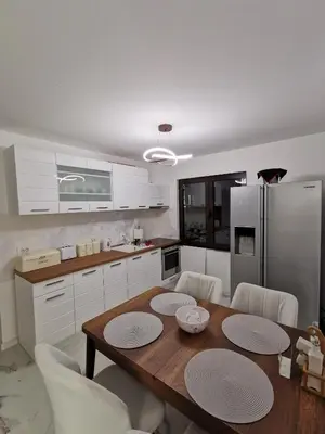 a kitchen with a wooden table and white cabinets at Excellent Time in Belgrade