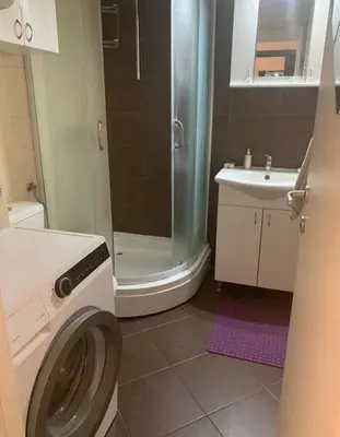a bathroom with a shower and a washing machine at Apartman ANN in Pančevo