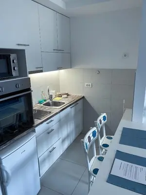 a kitchen with white cabinets and a sink and a table at Apartment Azzurro lux in Novi Beograd