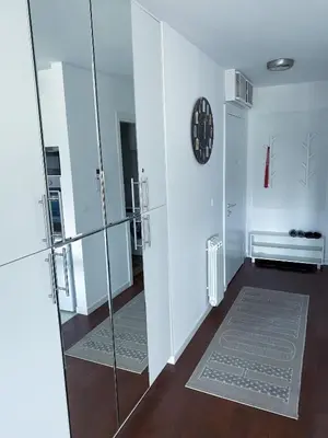 a hallway with a glass door and a clock on a wall at Apartment Azzurro lux in Novi Beograd