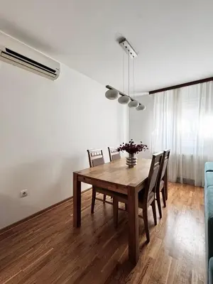 a dining room with a wooden table and chairs at Zemunske kapije 2 Prizrenska in Novi Grad