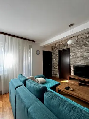 a living room with a blue couch and a television at Zemunske kapije 2 Prizrenska in Novi Grad