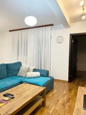a living room with a blue couch and a table at Zemunske kapije 2 Prizrenska in Novi Grad