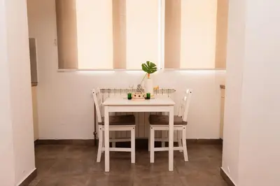 a white table and chairs in a room with windows at apartman Fuerte 2 in Belgrade