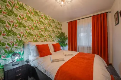 a bedroom with a bed with an orange blanket at Apartmani Maximilian in Čukarica