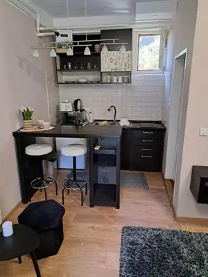 a small kitchen with a black counter and stools at Dvoriste Danguba in Nova Pazova
