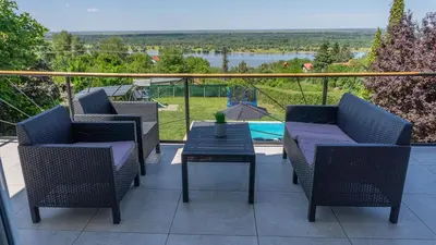 a patio with chairs and a table and a view of a river at Family House in Krčedin