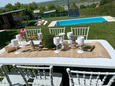 a table with white chairs and wine glasses on it at Family House in Krčedin
