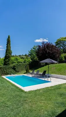 a swimming pool with two chairs and an umbrella at Family House in Krčedin
