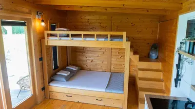 a bunk bed in a wooden cabin with a window at Woody House in Krčedin