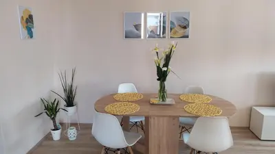 a dining room table with white chairs and a table with flowers at Diva apartman in Arandjelovac