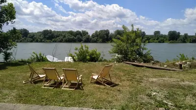 a group of chairs sitting in the grass near a lake at Top Chill party kucice apartmani in Belgrade