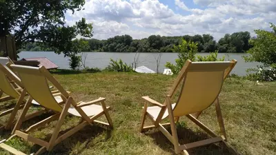 two chairs sitting in the grass next to a lake at Top Chill party kucice apartmani in Belgrade