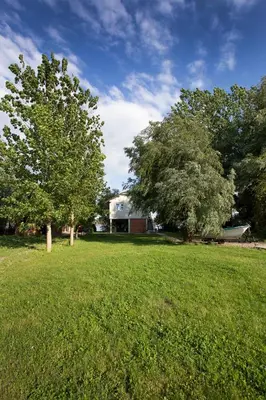 a field of grass with two trees and a building at River house Grana in Belgrade