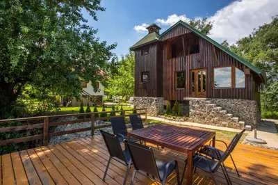 a wooden deck with a table and chairs in front of a house at River house Vasa in Belgrade