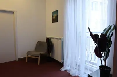 a room with a chair and a window with curtains at Belgrade Center Apartment Nusiceva in Belgrade