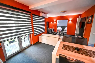 a room with orange walls and a living room with a couch at Respect034 in Arandjelovac