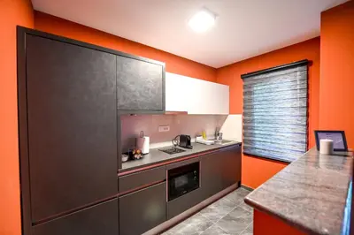 a kitchen with orange walls and a gray counter top at Respect034 in Arandjelovac