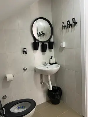 a bathroom with a toilet and a sink and a mirror at OMIS Rooms in Pančevo