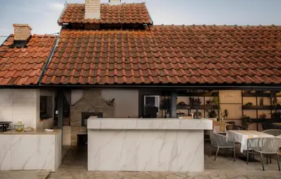 a house with a roof with a table and chairs at Vila Lio & Restaurant Devojacki Bunar in Novi Vladimirovac
