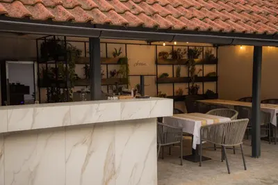 a restaurant with tables and chairs and a counter at Vila Lio & Restaurant Devojacki Bunar in Novi Vladimirovac