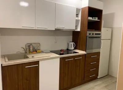 a small kitchen with white cabinets and a sink at Apartman Ambasador in Pančevo