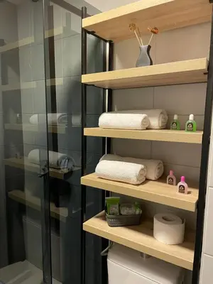 a bathroom with wooden shelves and towels at Apartman Ambasador in Pančevo