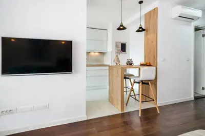 a kitchen with a table and a tv on a wall at A blok New Belgrade 2BD in Bežanija