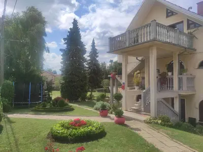 a house with a balcony and a yard with flowers at Andrea Airport Apartments in Belgrade
