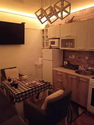 a small kitchen with a table and a refrigerator at Apartman EN in Dušanovac (historical)