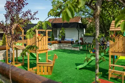 a yard with a playground with chairs and a house at Hotel GardeNN in Belgrade