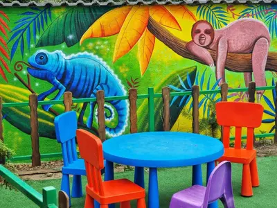 a colorful table and chairs in front of a mural at Hotel GardeNN in Belgrade