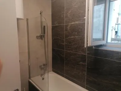 a bathroom with a shower with a tub and a window at Natasa in Zvezdara