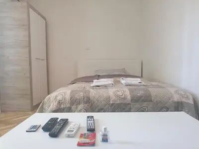 a bedroom with a bed with remotes on a table at Natasa in Zvezdara