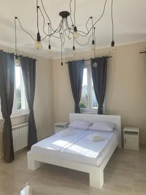 a bedroom with a white bed with black curtains at Vila Eleonora Beograd in Belgrade