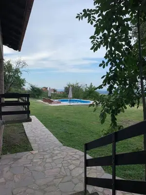 two benches sitting next to a park with a pool at Talin Raj in Arandjelovac