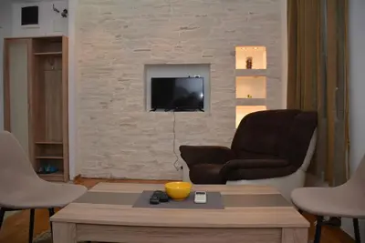 a living room with two chairs and a television on a brick wall at Obilic 22 Apartment in Belgrade