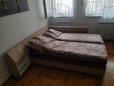 an unmade bed in a room with wooden floors at Belgradian 011 in Belgrade