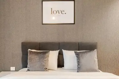 a bed with white pillows and a picture of love at Belgrade Waterfront Luxury Appartment Pool & Gym in Belgrade