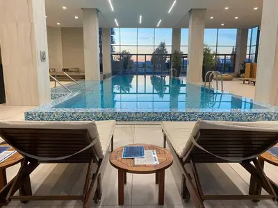 a swimming pool with two chairs and a table in front of it at Belgrade Waterfront Luxury Appartment Pool & Gym in Belgrade