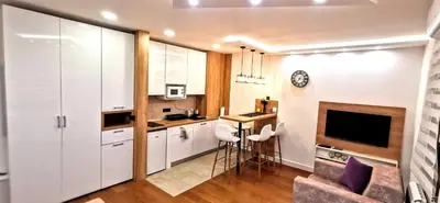 a kitchen with white cabinets and a table in a room at MOON LUX Apartman Beograd in Belgrade
