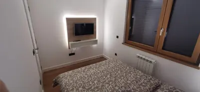 a small room with a bed and a tv on the wall at MOON LUX Apartman Beograd in Belgrade