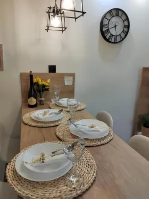a table with plates and glasses on it with a clock at MOON LUX Apartman Beograd in Belgrade