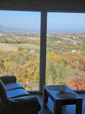a living room with a couch and a table and a large window at Vila POGLED in Arandjelovac
