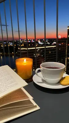 a cup of coffee and a book on a table with a candle at DOM Boutique Apartments PARK VIEW in Belgrade